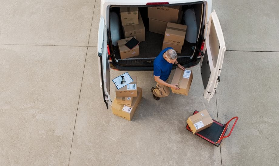 supply chain finance - logistics worker loading packages into a commercial vehicle