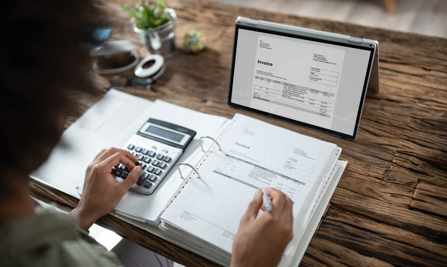 Businessman's Hands Working On Invoice On Laptop